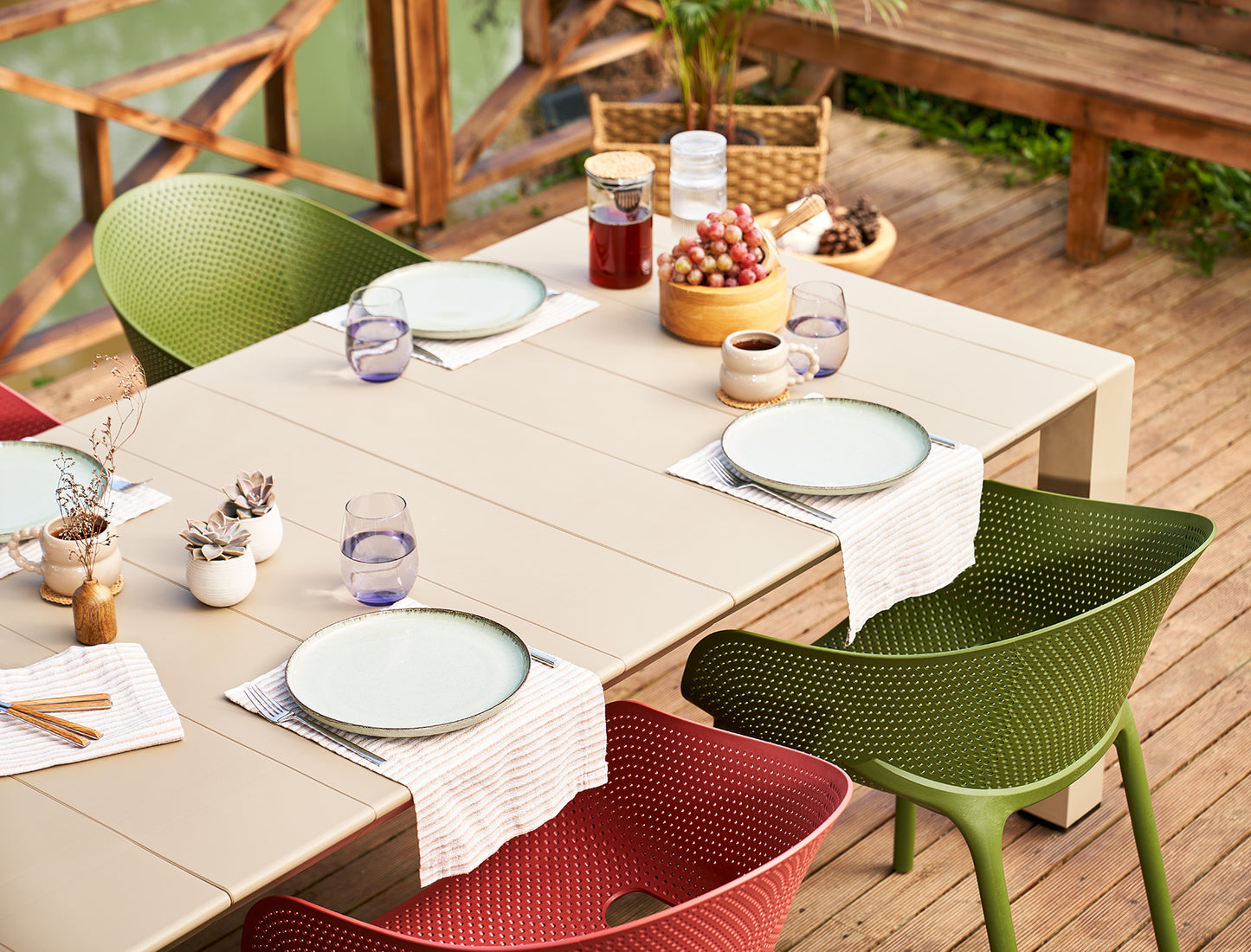 Dining table set with plates, glasses, and food on a wooden deck