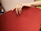 Close-up of a hand holding a red perforated chair