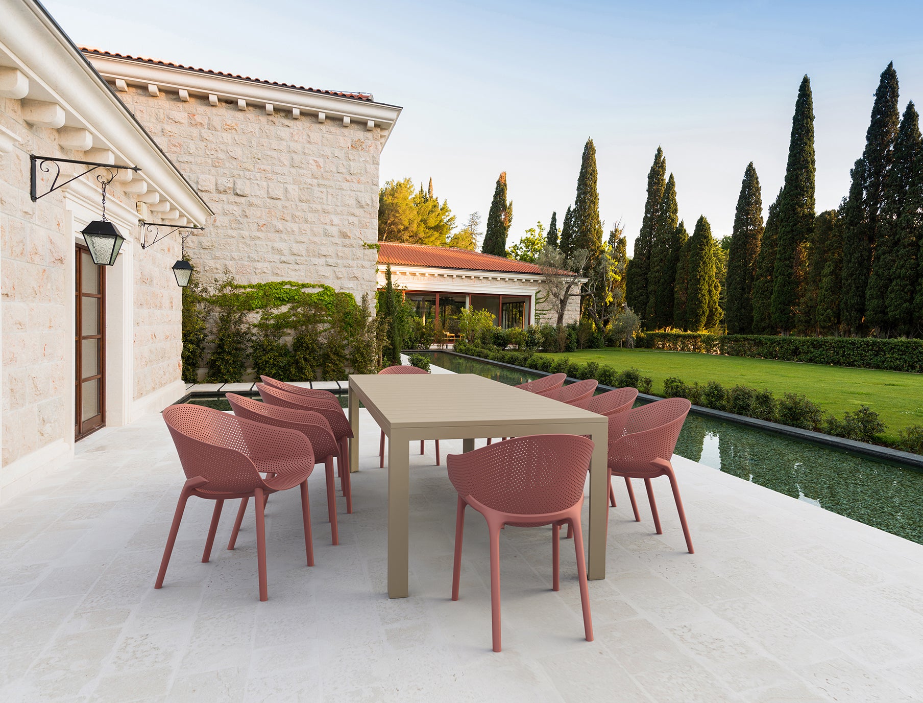 Outdoor dining set with pink chairs and a beige table on a patio.