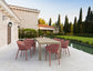 Outdoor dining set with pink chairs and a beige table on a patio.