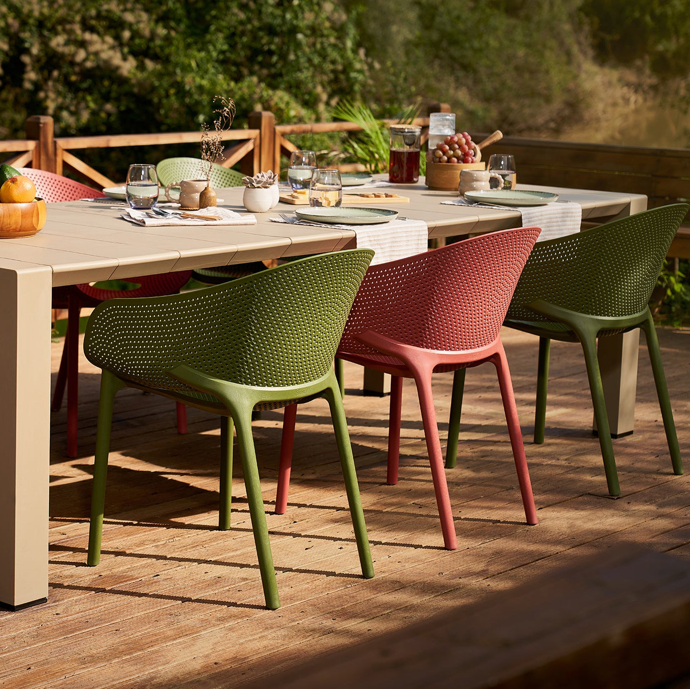 Outdoor dining table with colorful chairs on a wooden deck