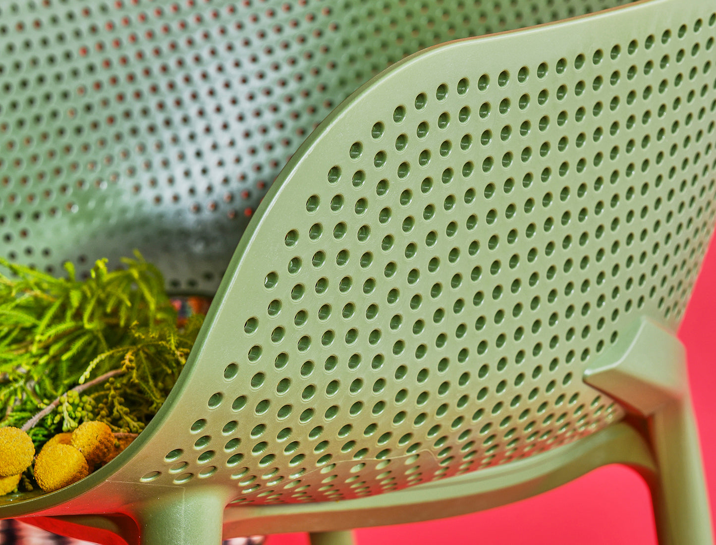 Close-up of a green colander with holes on a red background