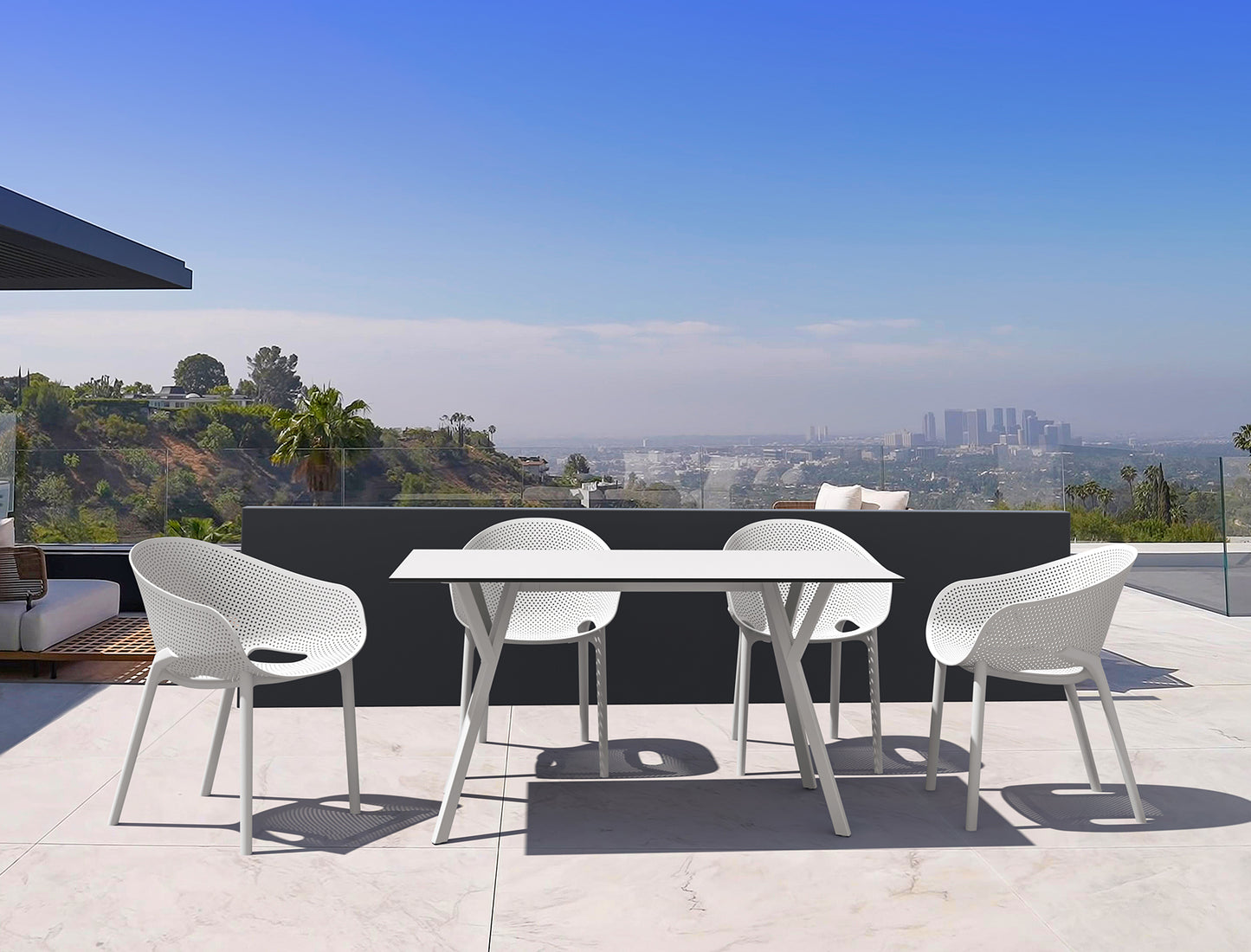 Outdoor dining set with white chairs and table on a terrace with a cityscape view.