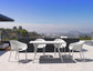 Outdoor dining set with white chairs and table on a terrace with a cityscape view.