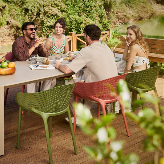 Group of people sitting around a table outdoors with green chairs.