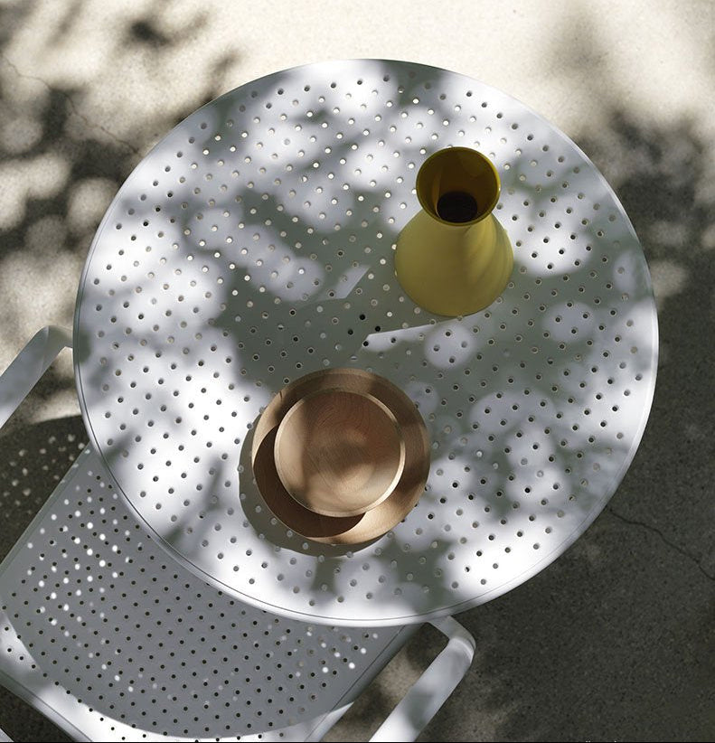 Round perforated metal table with decorative items, featuring Nardi branding.