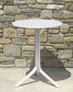 White round table with a star-shaped base against a stone wall.
