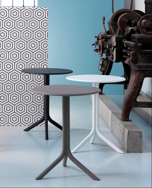 Set of colorful side tables against a geometric patterned wall.