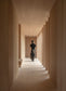 Person walking down a long, narrow hallway with columns