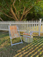 Outdoor furniture set with striped chair and ottoman on grass, white picket fence in background