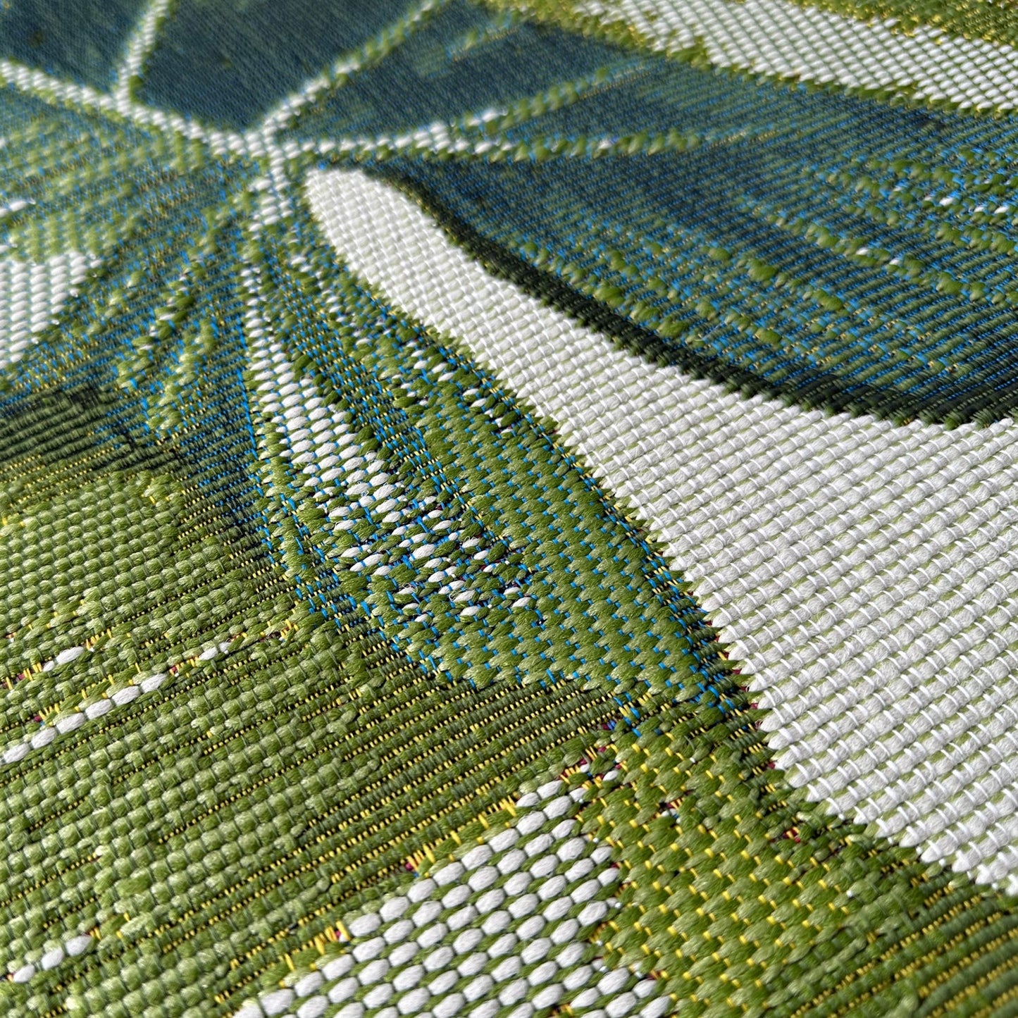 Close-up of a woven fabric with green, white, and blue pattern