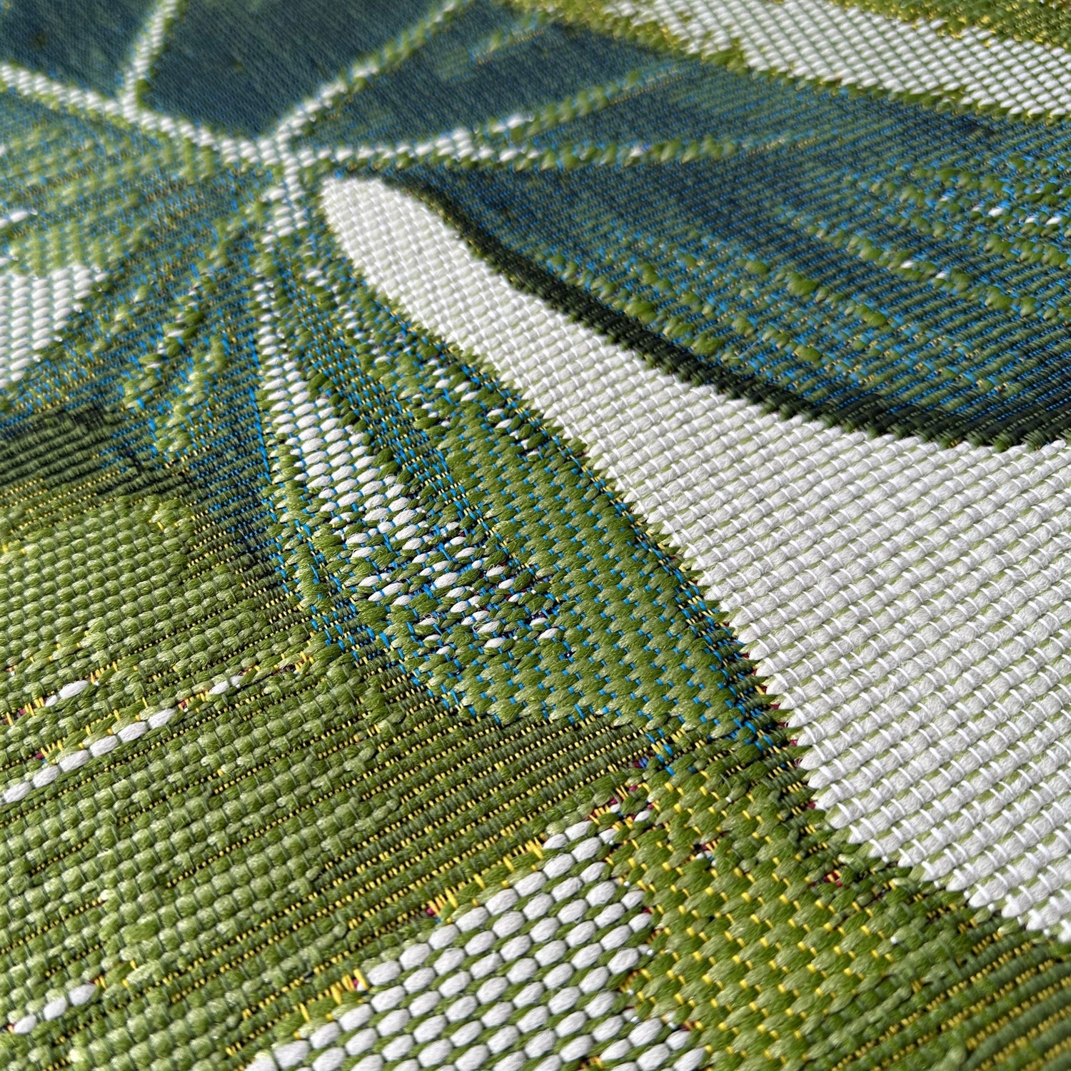 Close-up of a woven fabric with green, white, and blue pattern