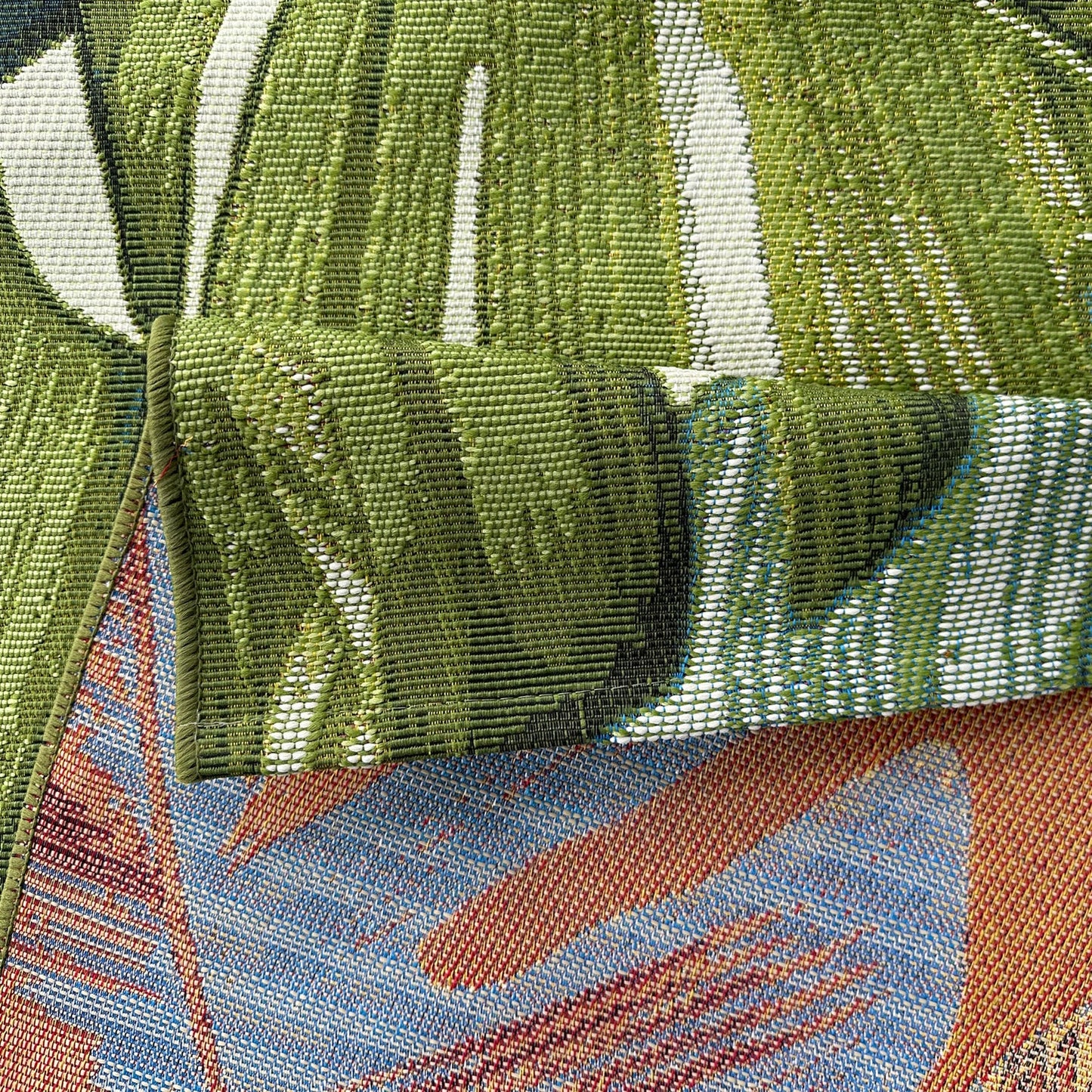 Close-up of a fabric with a tropical leaf pattern featuring green, blue, and brown colors.