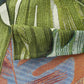 Close-up of a fabric with a tropical leaf pattern featuring green, blue, and brown colors.