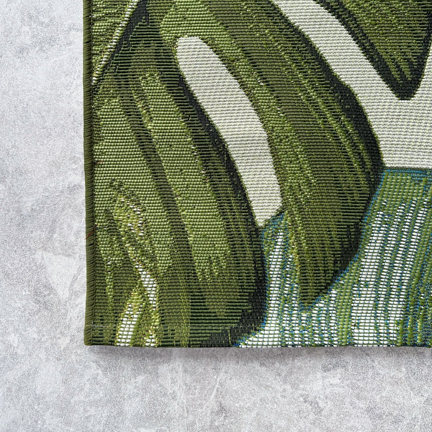 Close-up of a green and white patterned rug on a textured surface