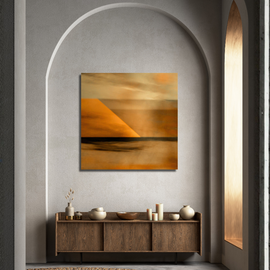 An abstract landscape art print featuring a warm orange and yellow desert scene, displayed on a textured gray wall in a modern interior setting above a wooden console table.