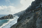 Scenic view of a rocky coastline with people on a cliff edge.
