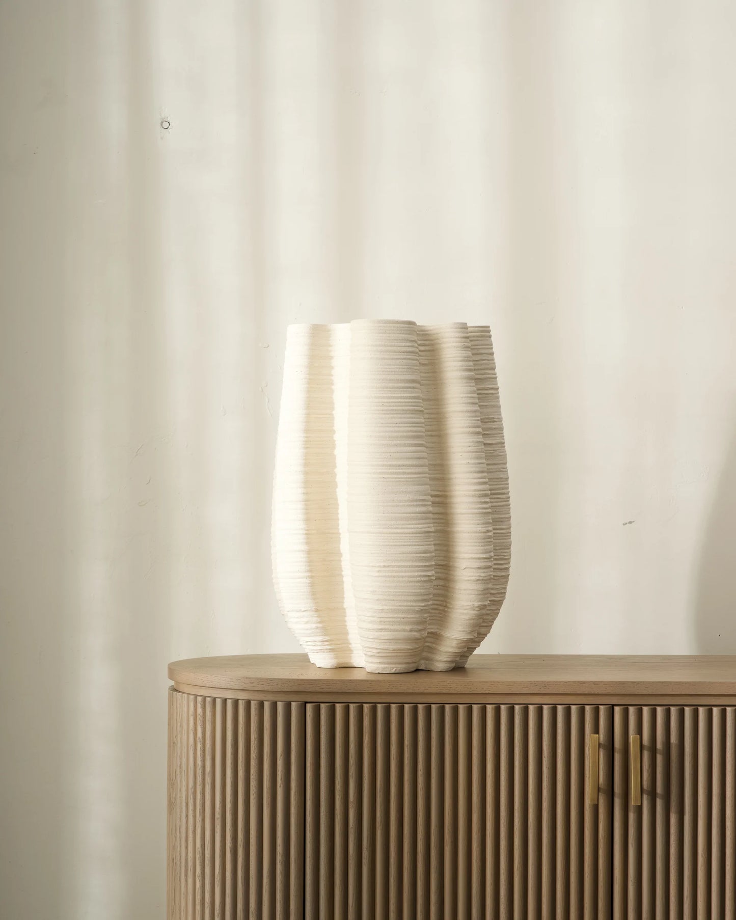 Decorative vase on a wooden cabinet against a plain wall