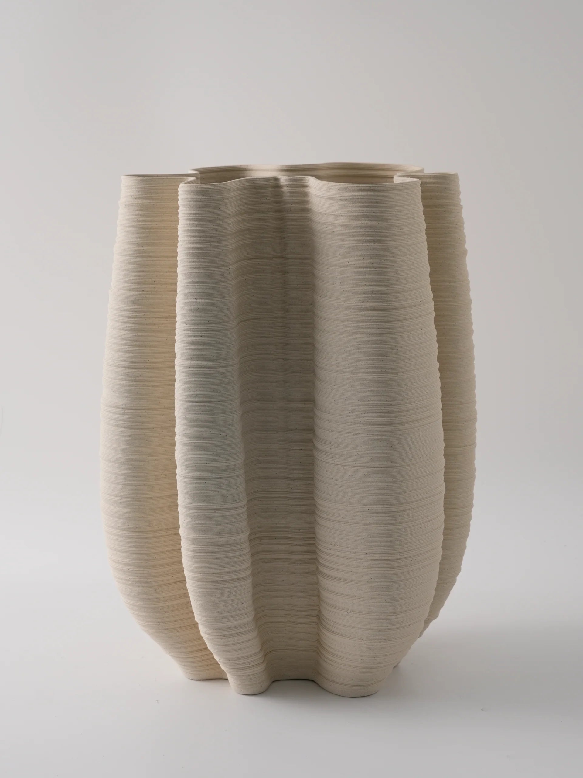 Beige ceramic vase with textured surface on a light gray background