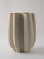Beige ceramic vase with textured surface on a light gray background