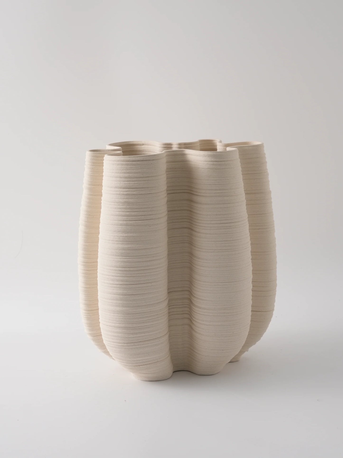 Beige ceramic vase with ribbed texture on a light gray background