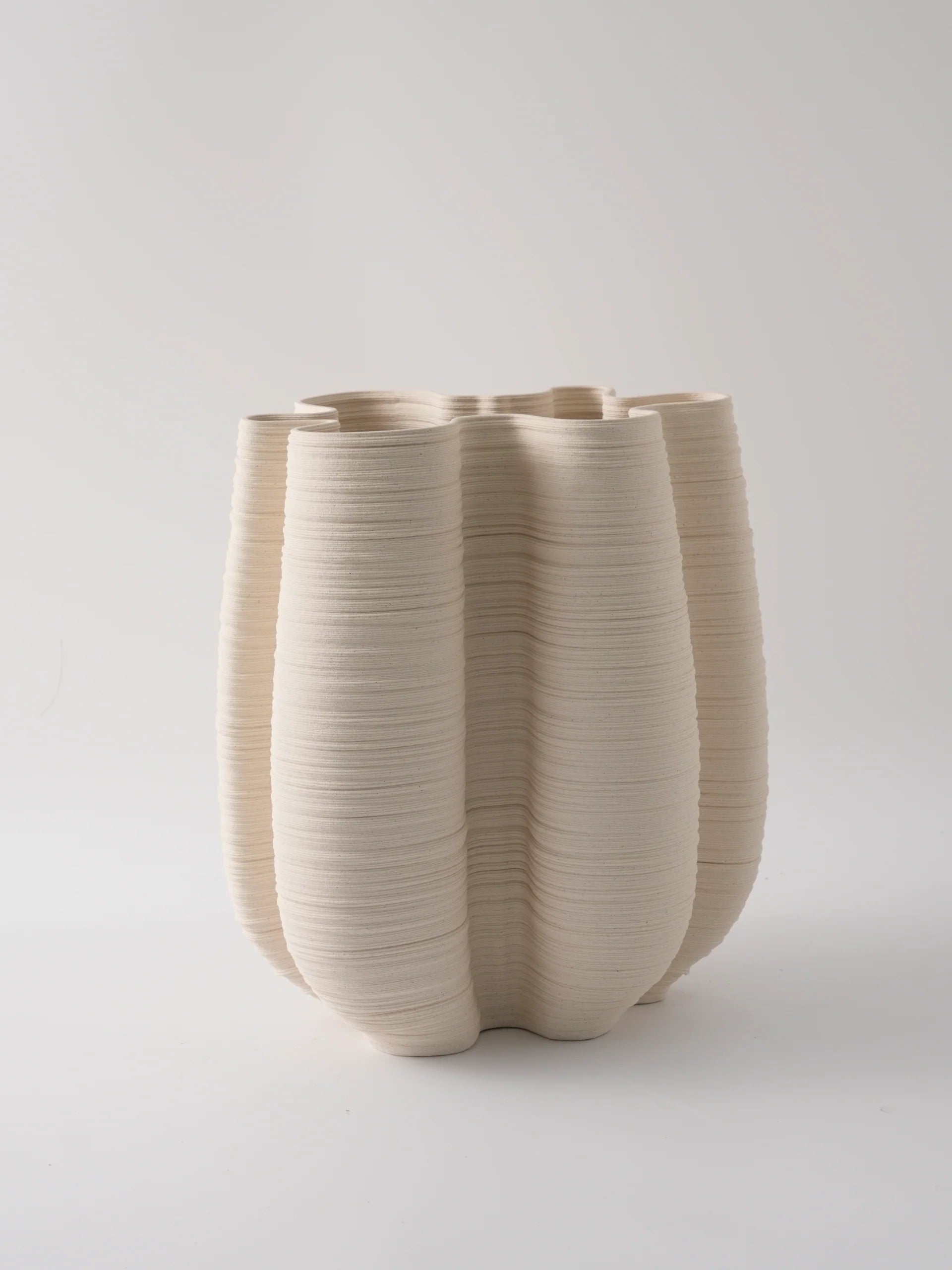 Beige ceramic vase with ribbed texture on a light gray background