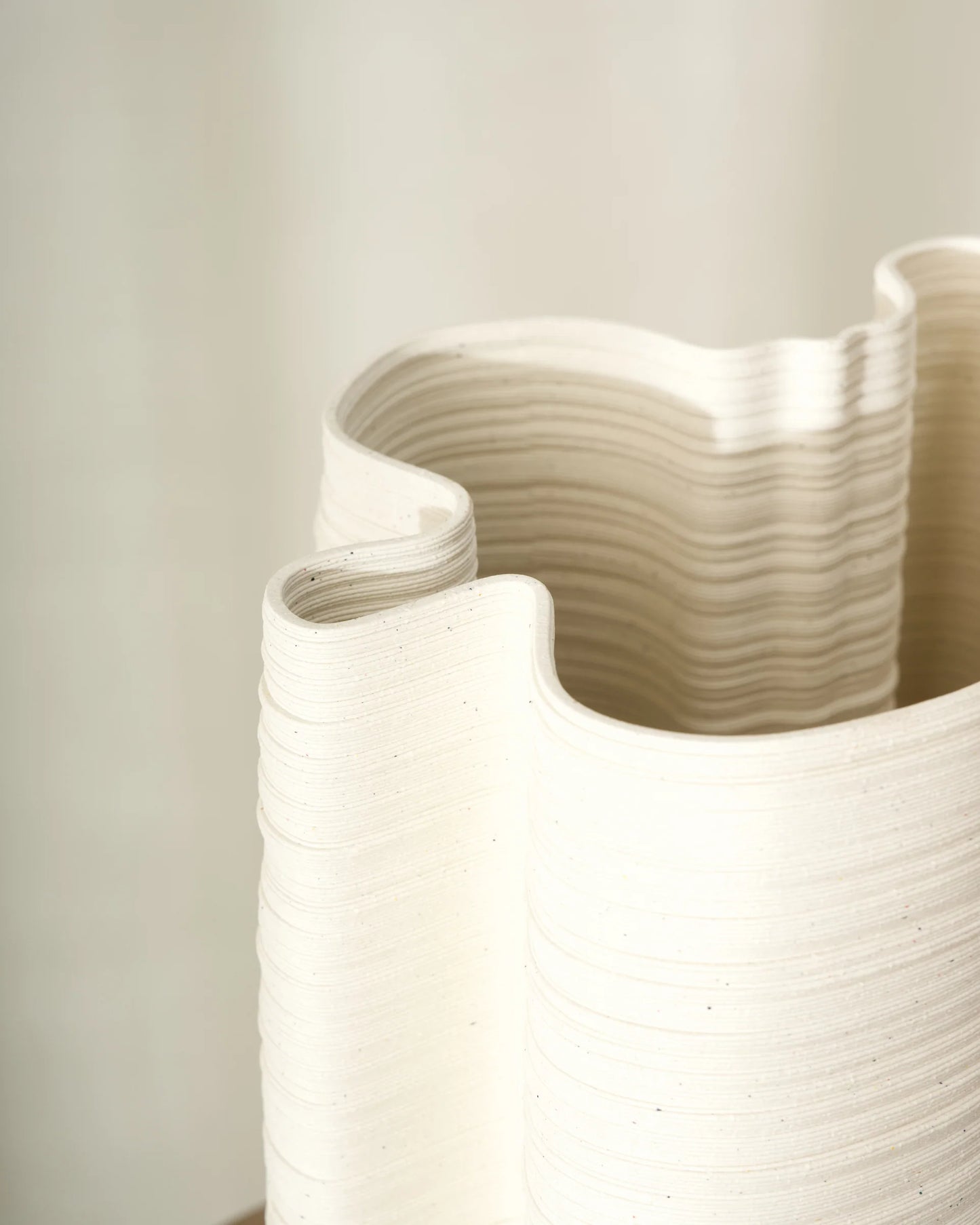 White ceramic vase with wavy design on a light gray background