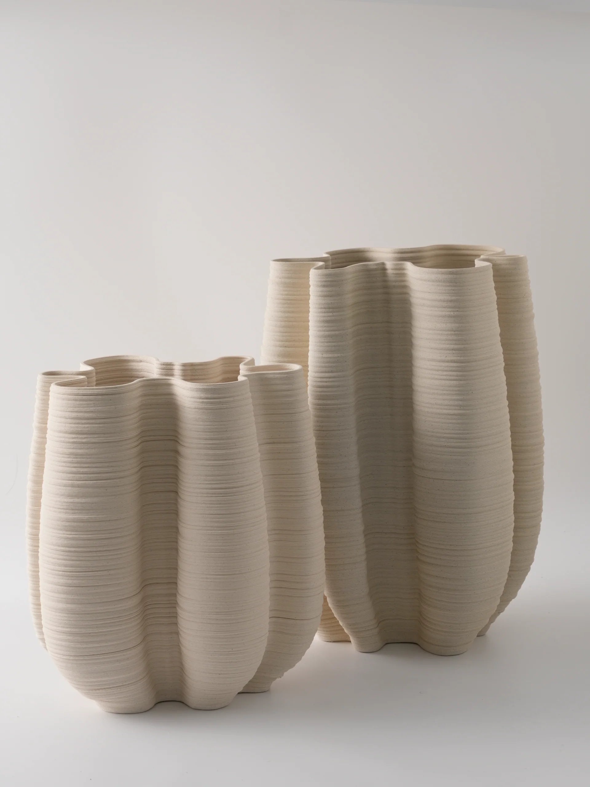 Set of three beige ceramic vases with textured surface on a white background