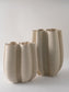 Set of three beige ceramic vases with textured surface on a white background