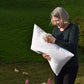 Lady holding a pillow that has a pure wool insert with sheep and hills in the background