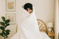 Person wrapped in a blanket with a headband in a bedroom setting