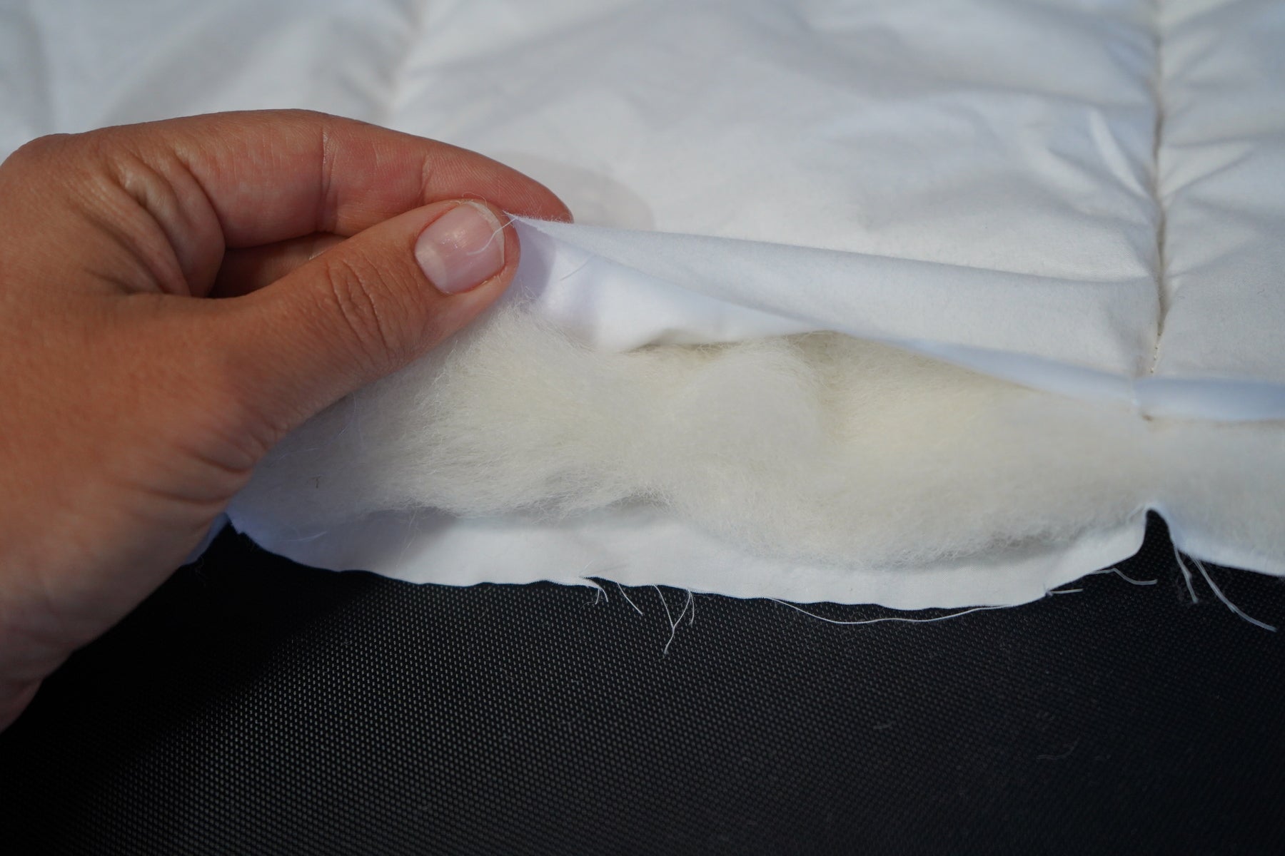 Close-up of a hand holding a white fabric strip against a black background