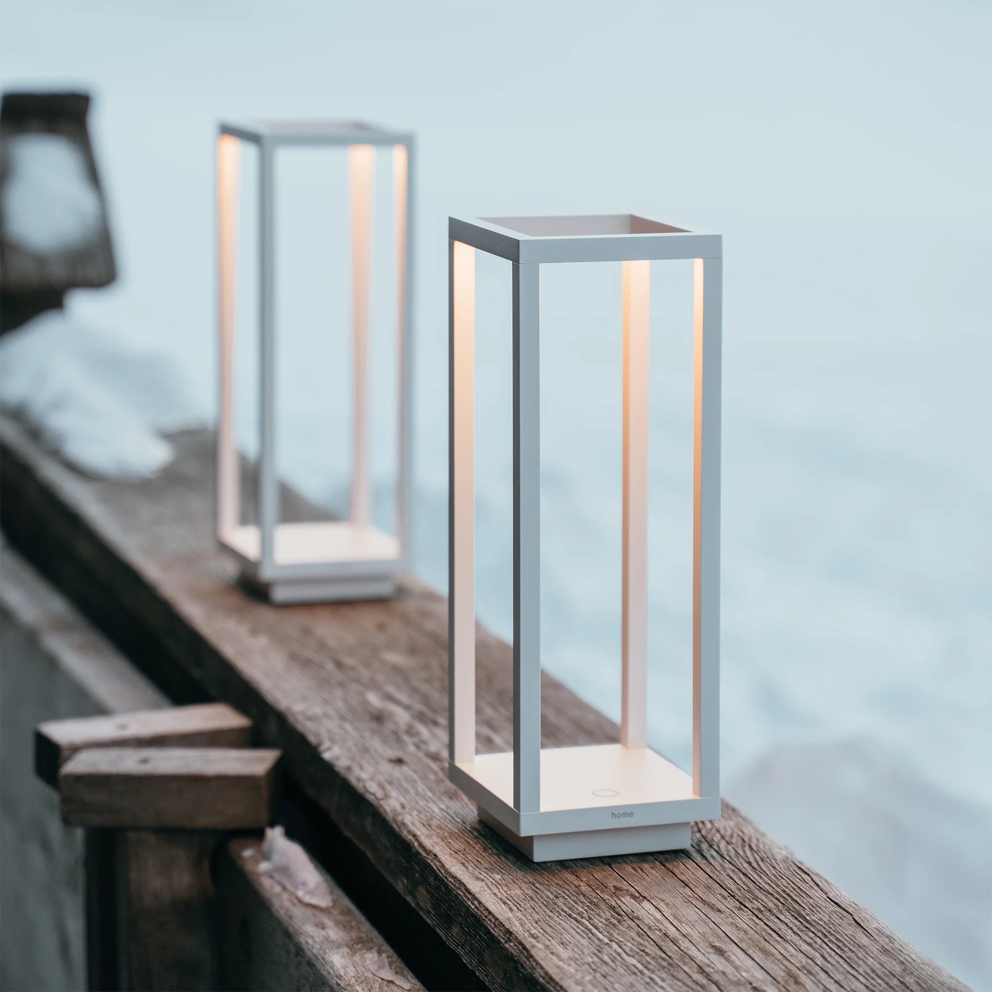 Two modern outdoor lamps on a wooden surface with a blurred natural background