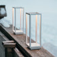 Two modern outdoor lamps on a wooden surface with a blurred natural background