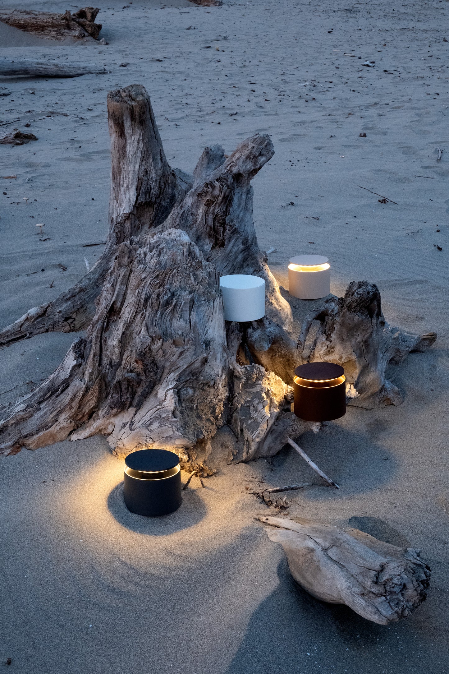 Driftwood with illuminated candles on a sandy beach