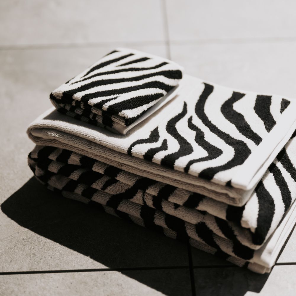 Stack of black and white patterned towels on a tiled floor