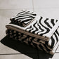 Stack of black and white patterned towels on a tiled floor