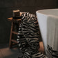 Zebra-patterned towel draped over a wooden stool next to a white bathtub.