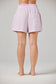 Person wearing light purple shorts on a plain background