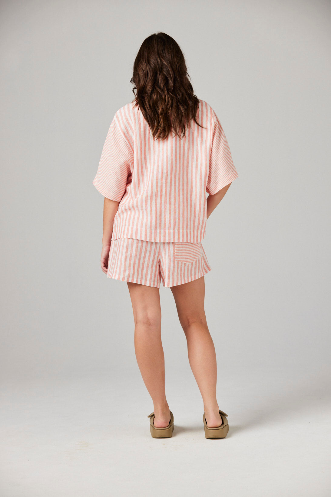Woman wearing a pink striped outfit on a plain background