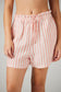 Person wearing pink and white striped shorts on a plain background
