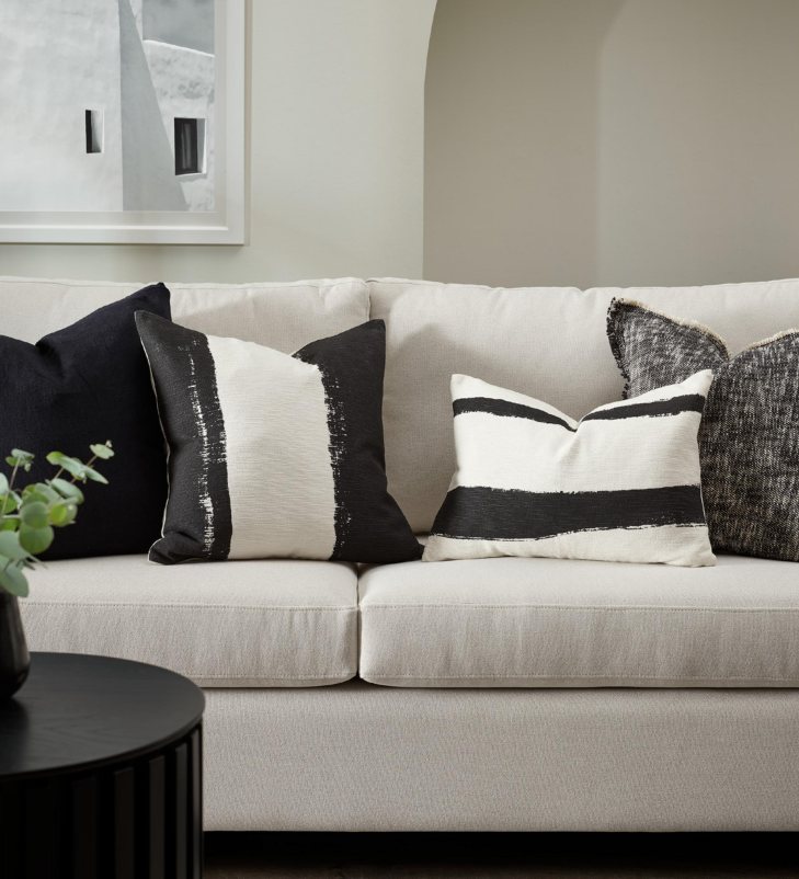 White sofa with black and white patterned cushions in a living room setting.