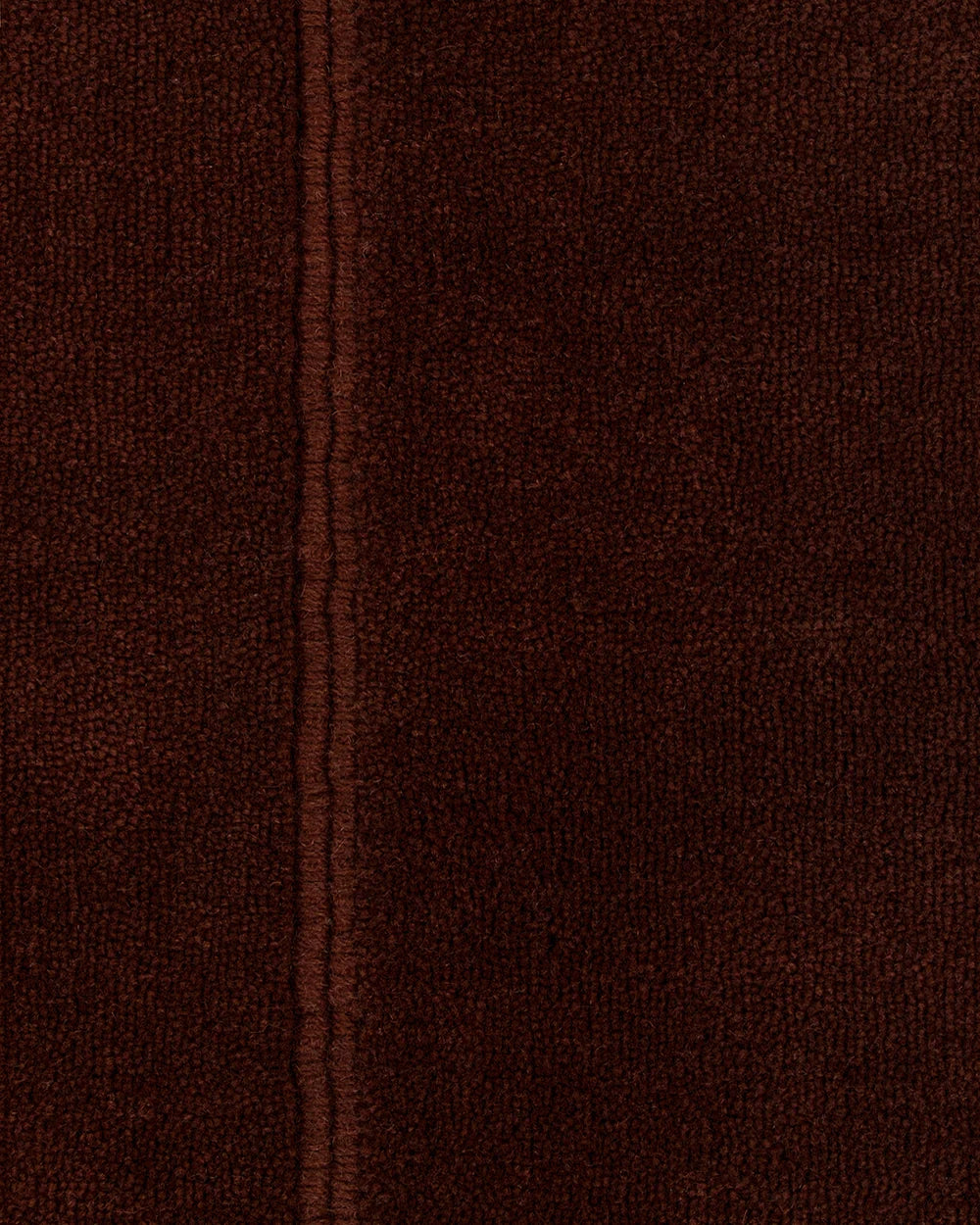 A close-up of dark brown textured rug with a vertical stitched seam running down the center.