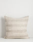 Textured pillow with a neutral color palette on a light gray background
