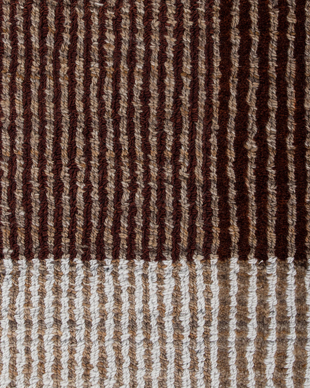 Close-up of a woven textile with vertical ribbed stripes in dark brown, medium brown, tan, and off-white, with a lighter striped border at the bottom.