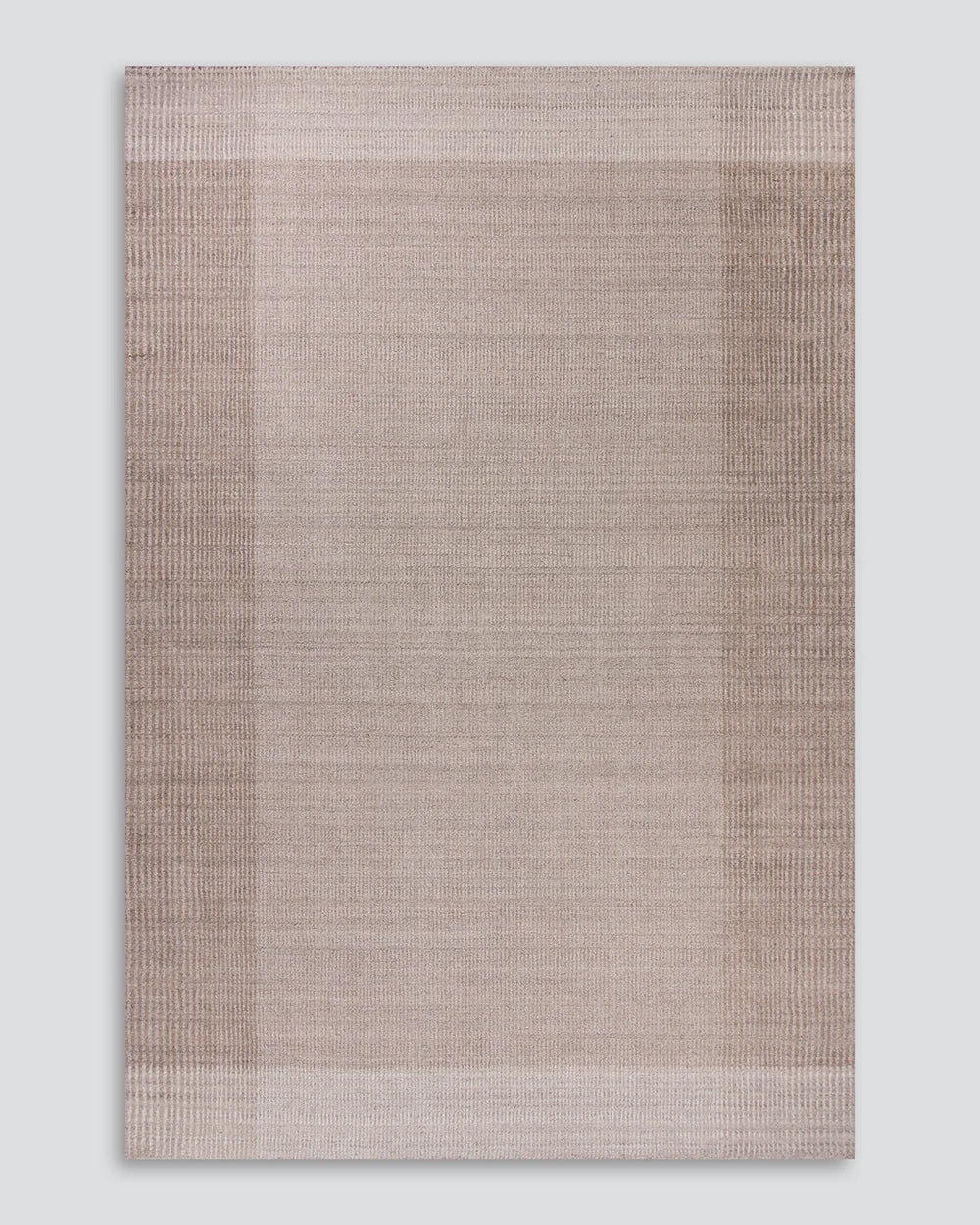 A rectangular woven rug with a textured, horizontal ribbed pattern in shades of taupe and light brown, featuring a subtle border design, shown against a neutral light gray background.