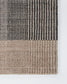 Close-up of a textured woven rug corner showing a striped pattern in dark charcoal gray and warm beige on a white background.