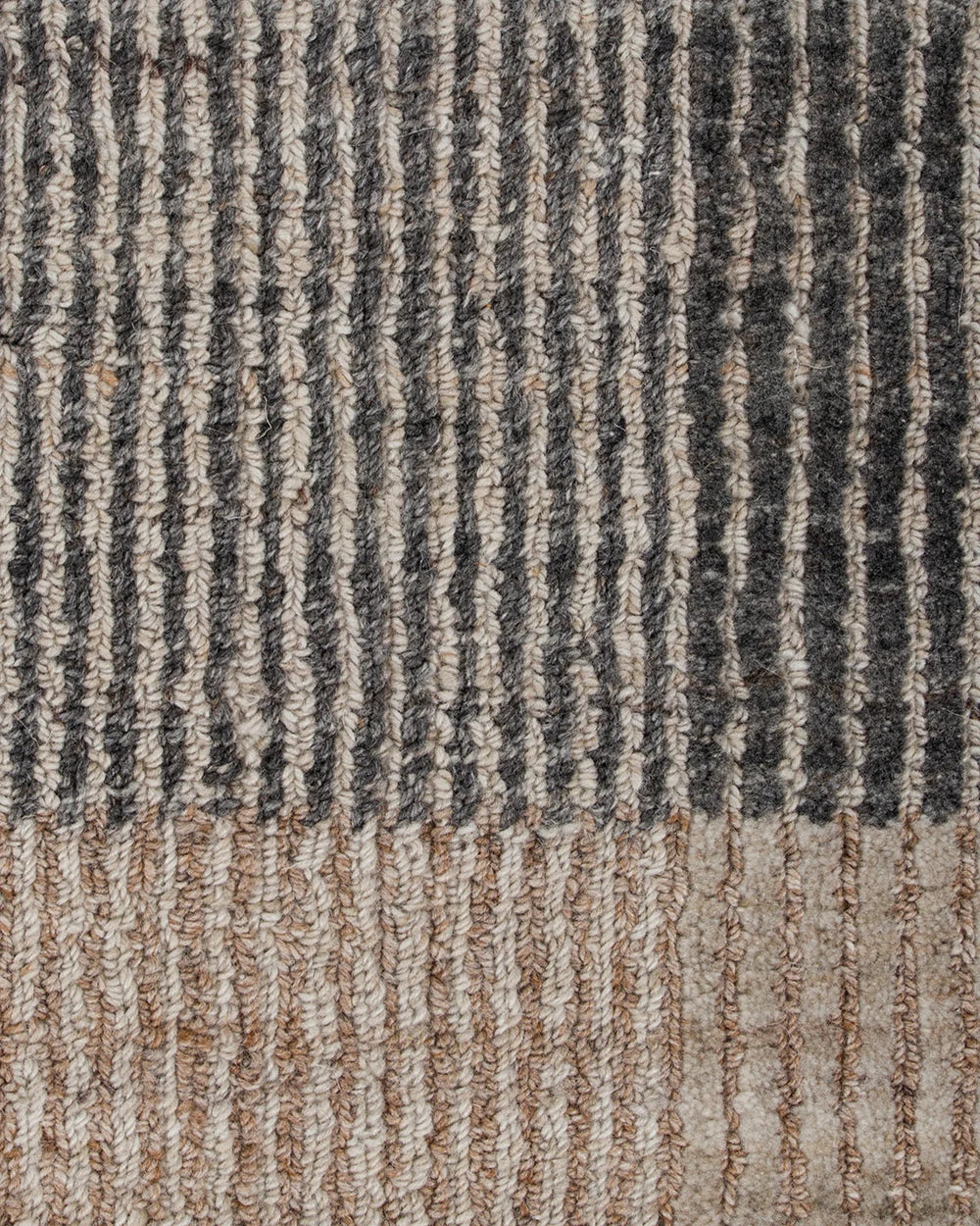 Close-up of a textured woven rug with vertical ribbed stripes in dark charcoal gray, beige, and light taupe.