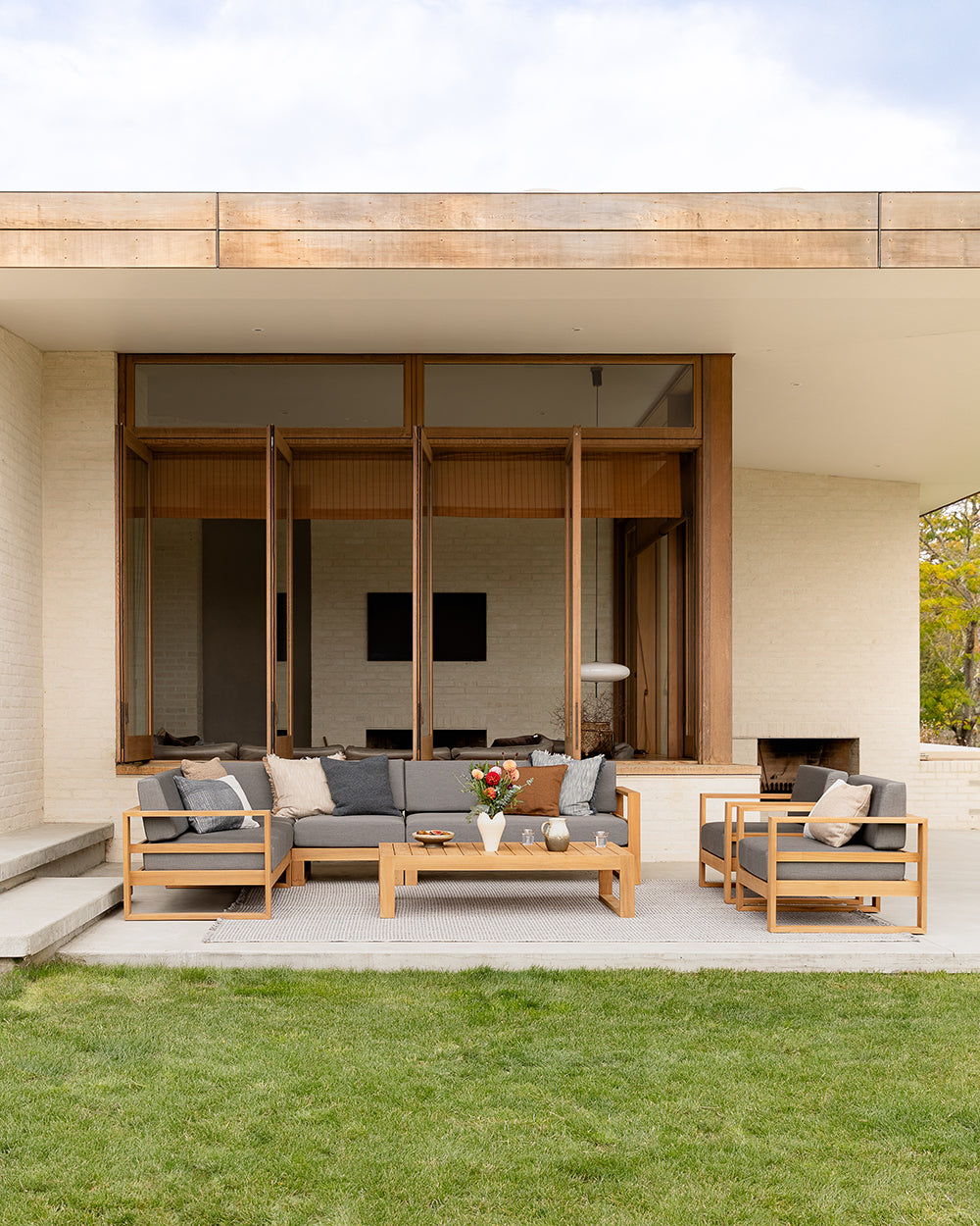 Modern outdoor living space with wooden furniture and a glass wall.