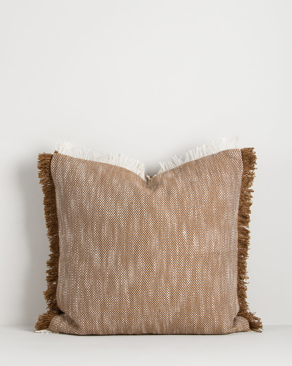 Textured pillow with fringes on a white background